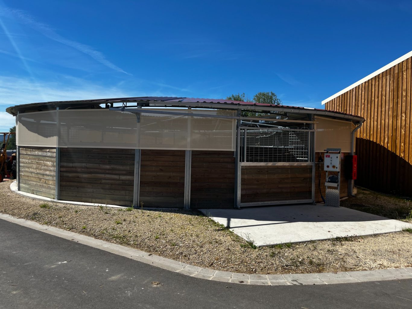 Marcheur Bâtiment moderne avec façade en béton et bois, situé au milieu d'un paysage dégagé.