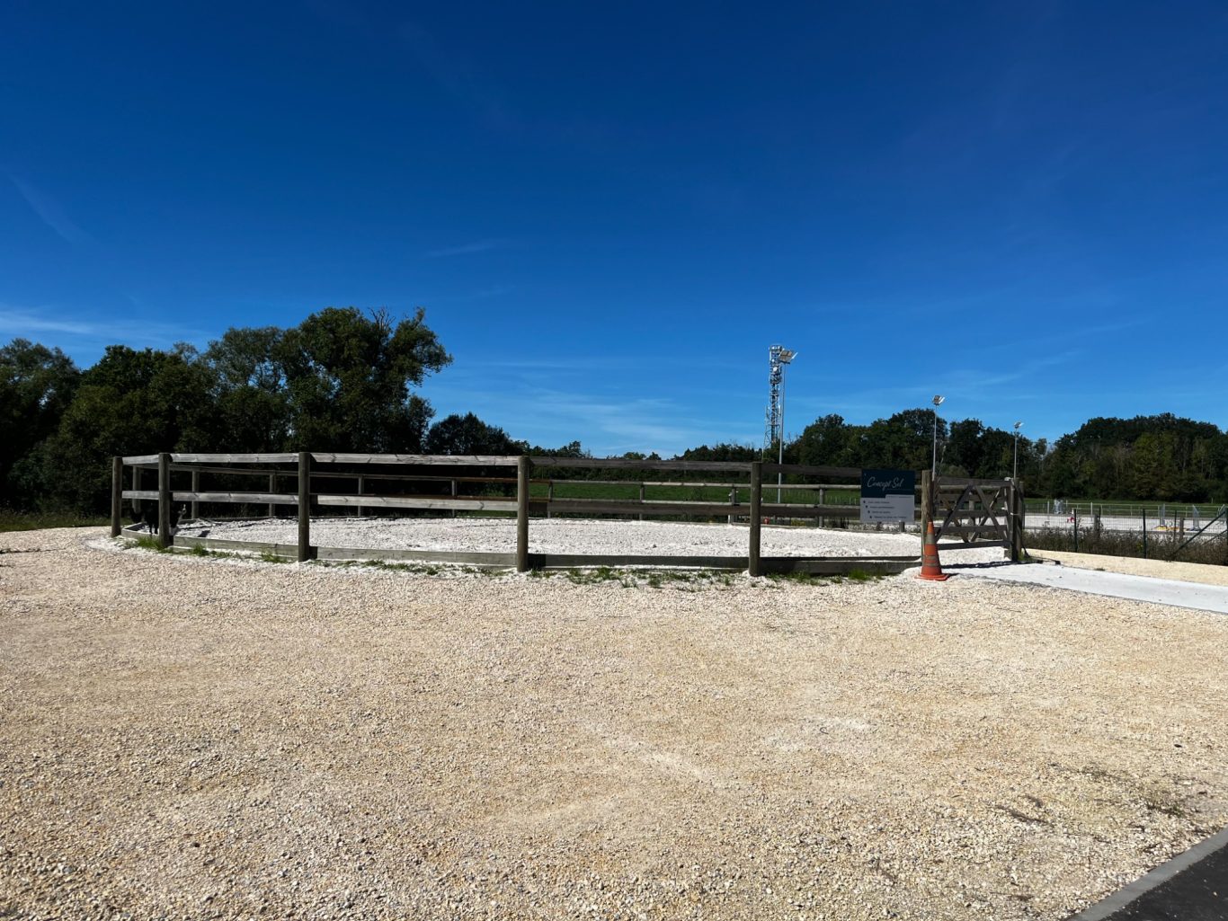 Rond de longe Manège en plein air avec des clôtures en bois sous un ciel bleu dégagé.